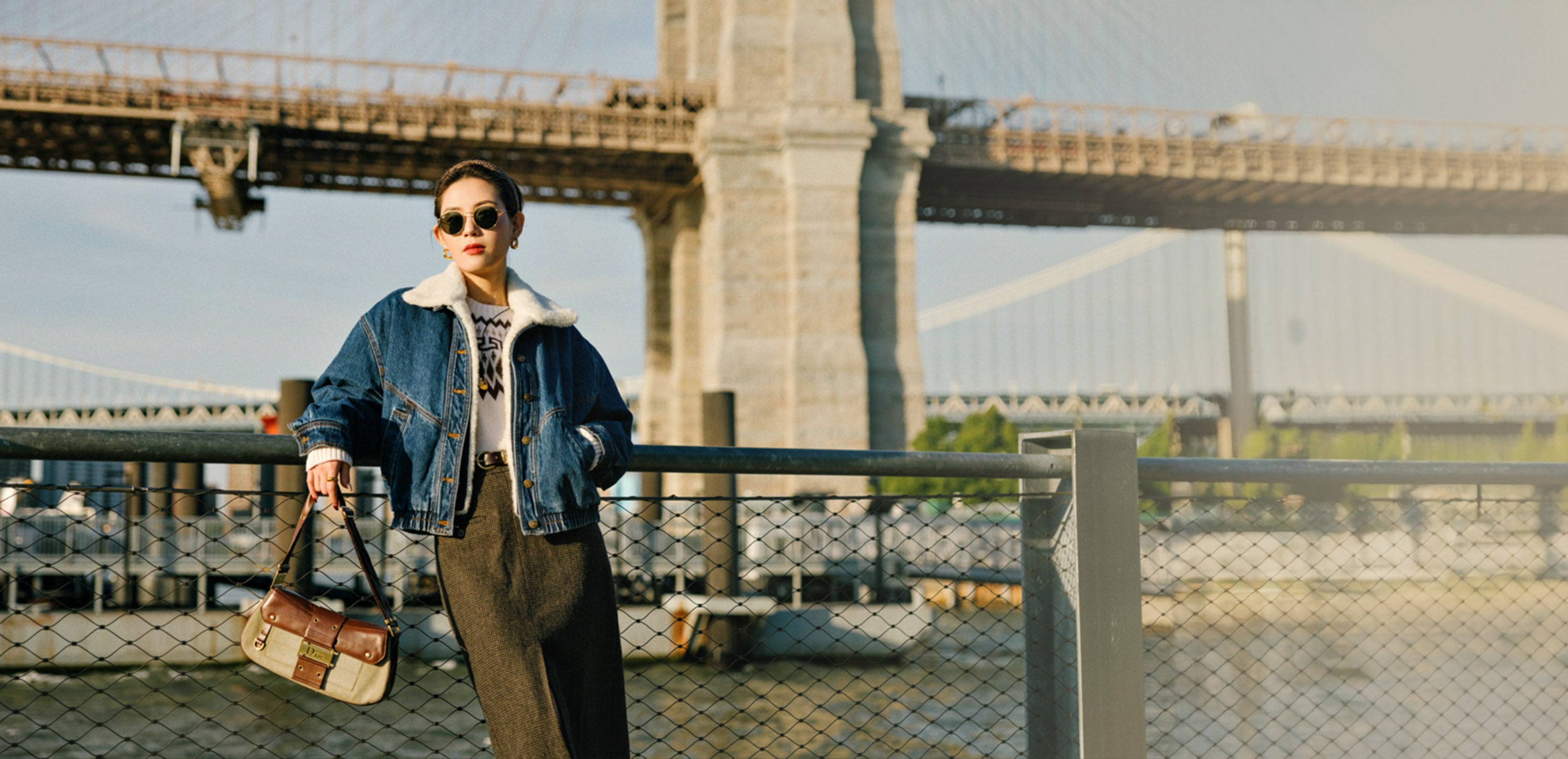 Model standing in front of Brooklyn Bridge wearing Petite Studio denim jacket